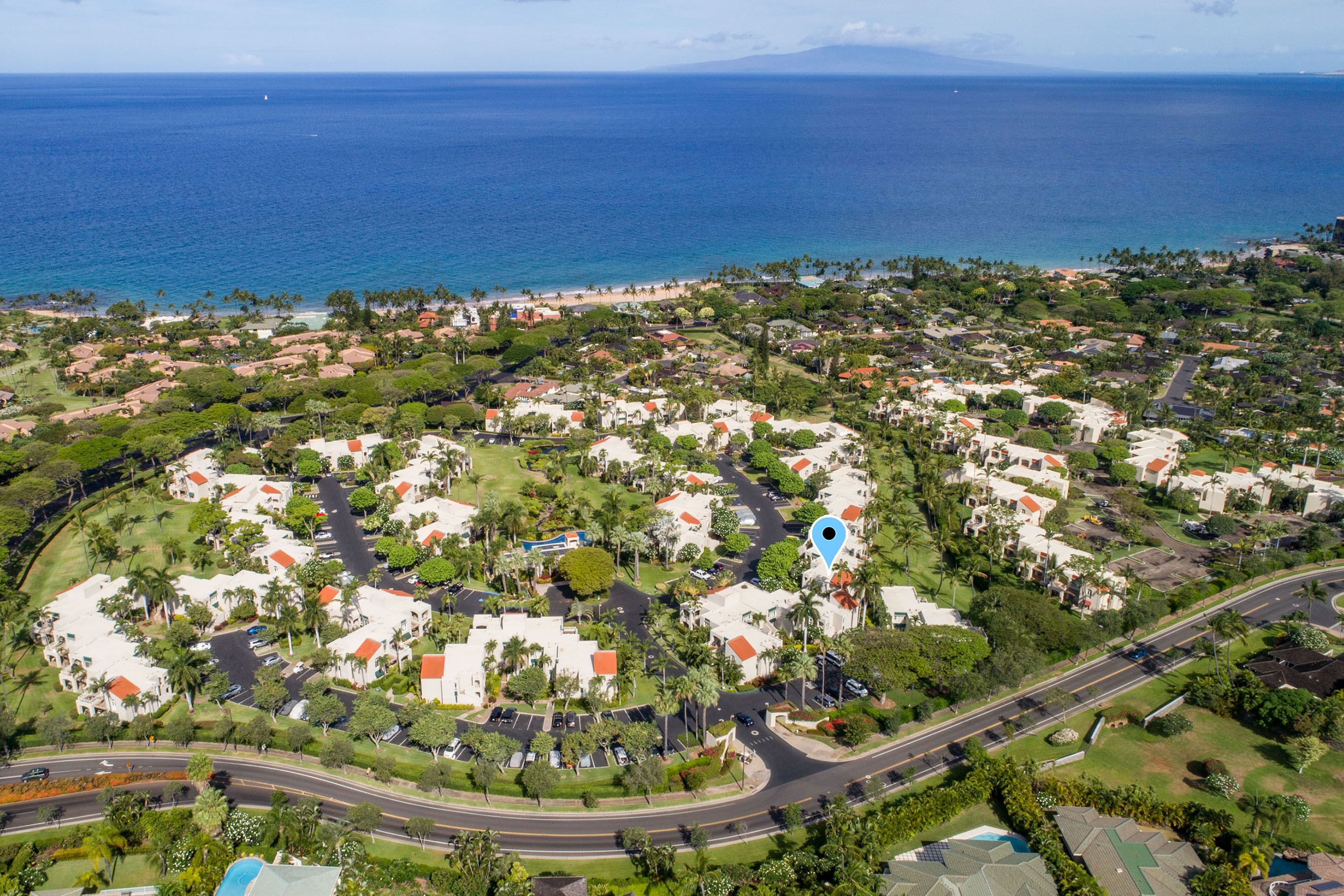 An aerial view of a coastal residential area with houses, roads, and a beach.