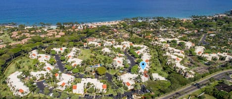 An aerial view of a coastal residential area with houses, roads, and a beach.