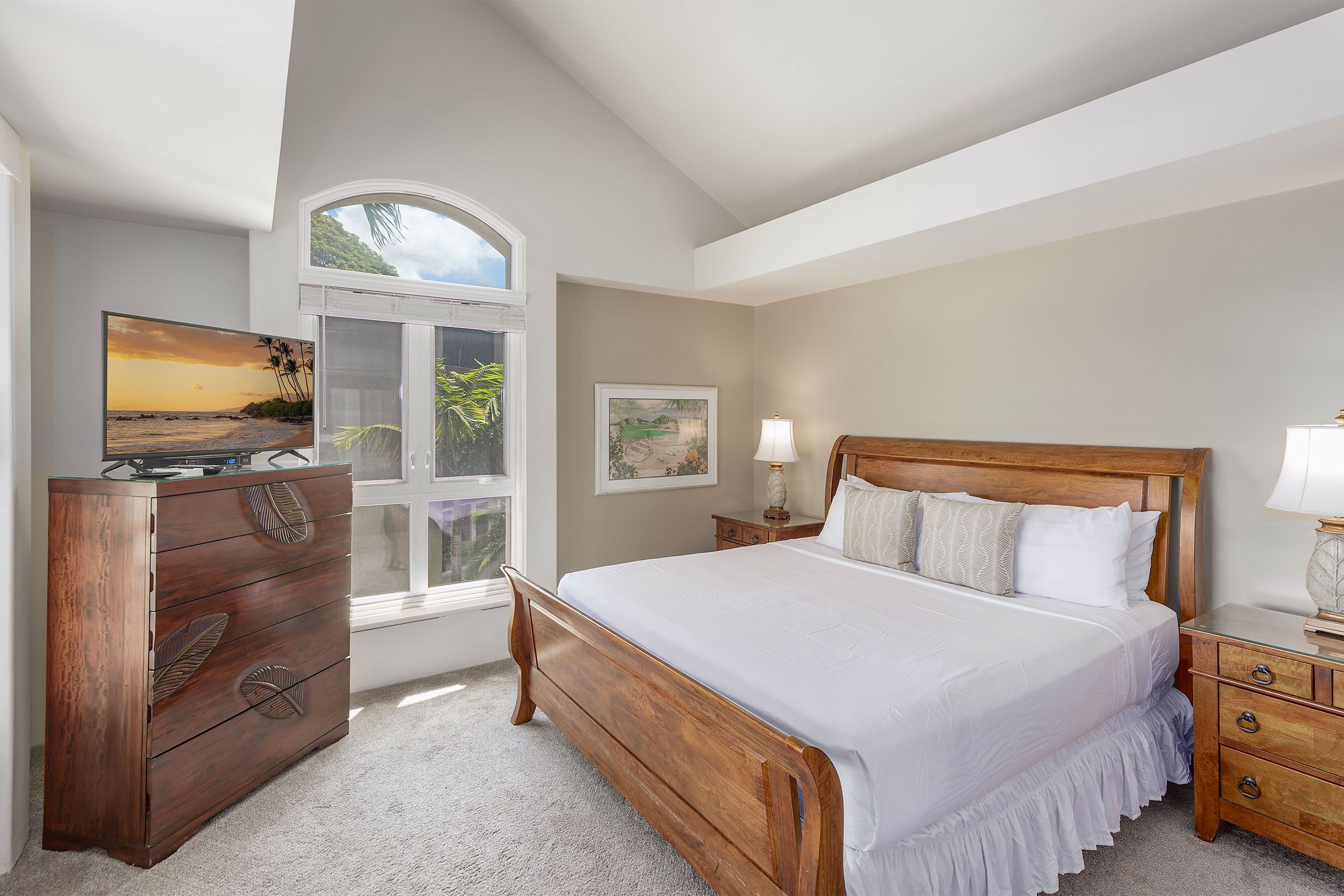 A bedroom with a wooden bed, a dresser, a nightstand, a window with a view of the outdoors, and a painting on the wall.