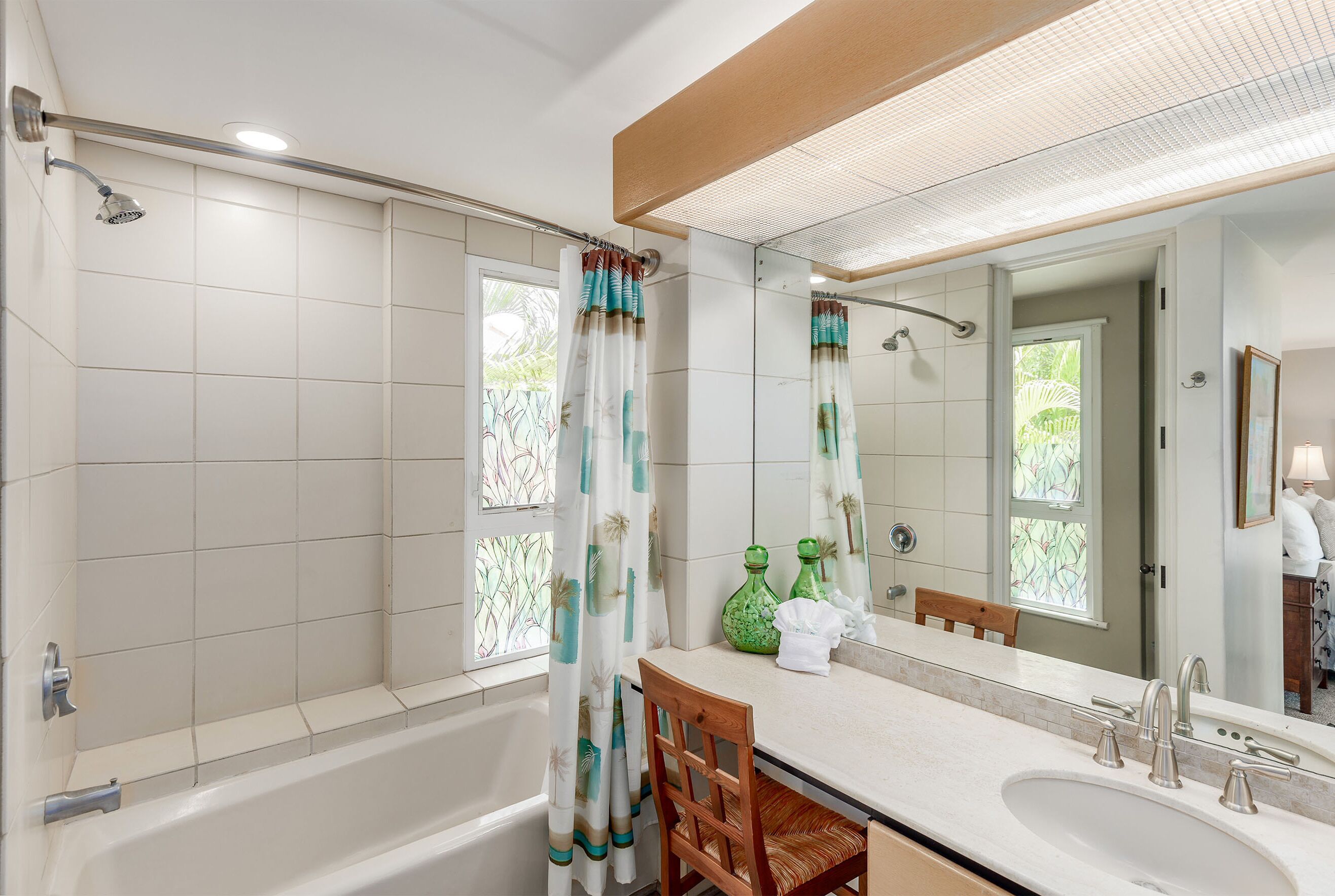 A bathroom with a bathtub, a sink with a mirror, and a shower with a curtain.