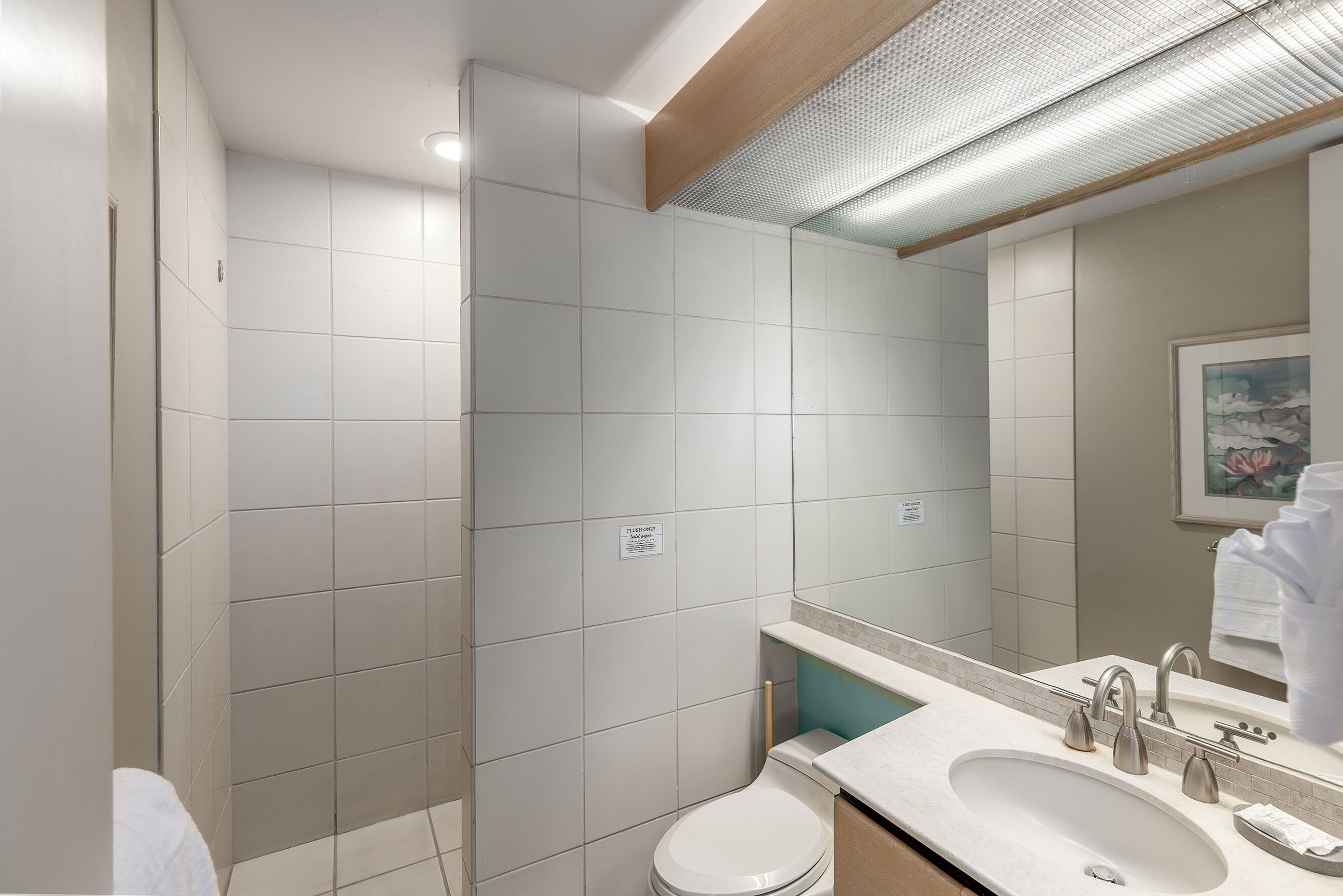 Een moderne badkamer met toilet, wastafel en spiegel.