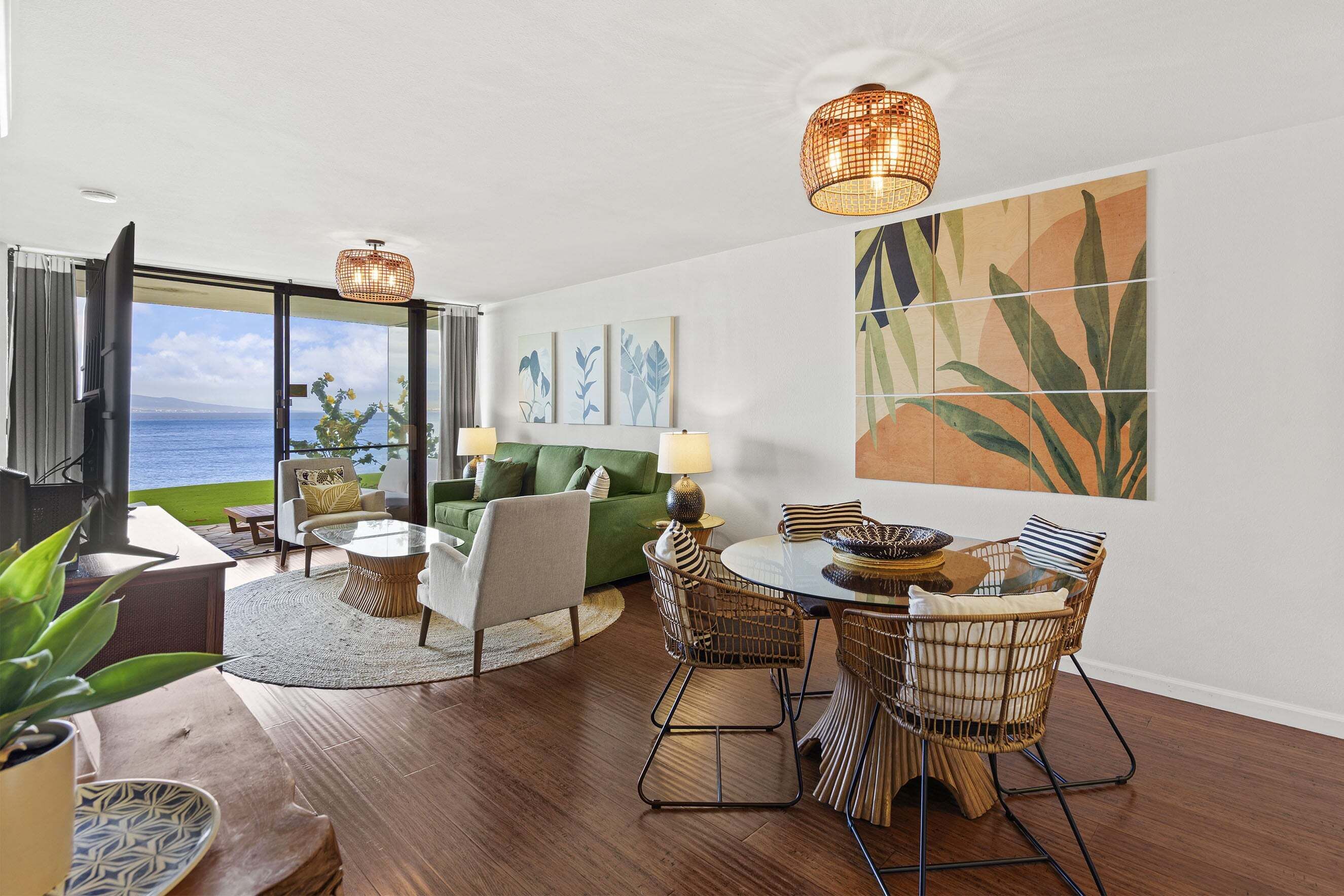 A modern living room with a dining area, large windows, and a view of the sea.