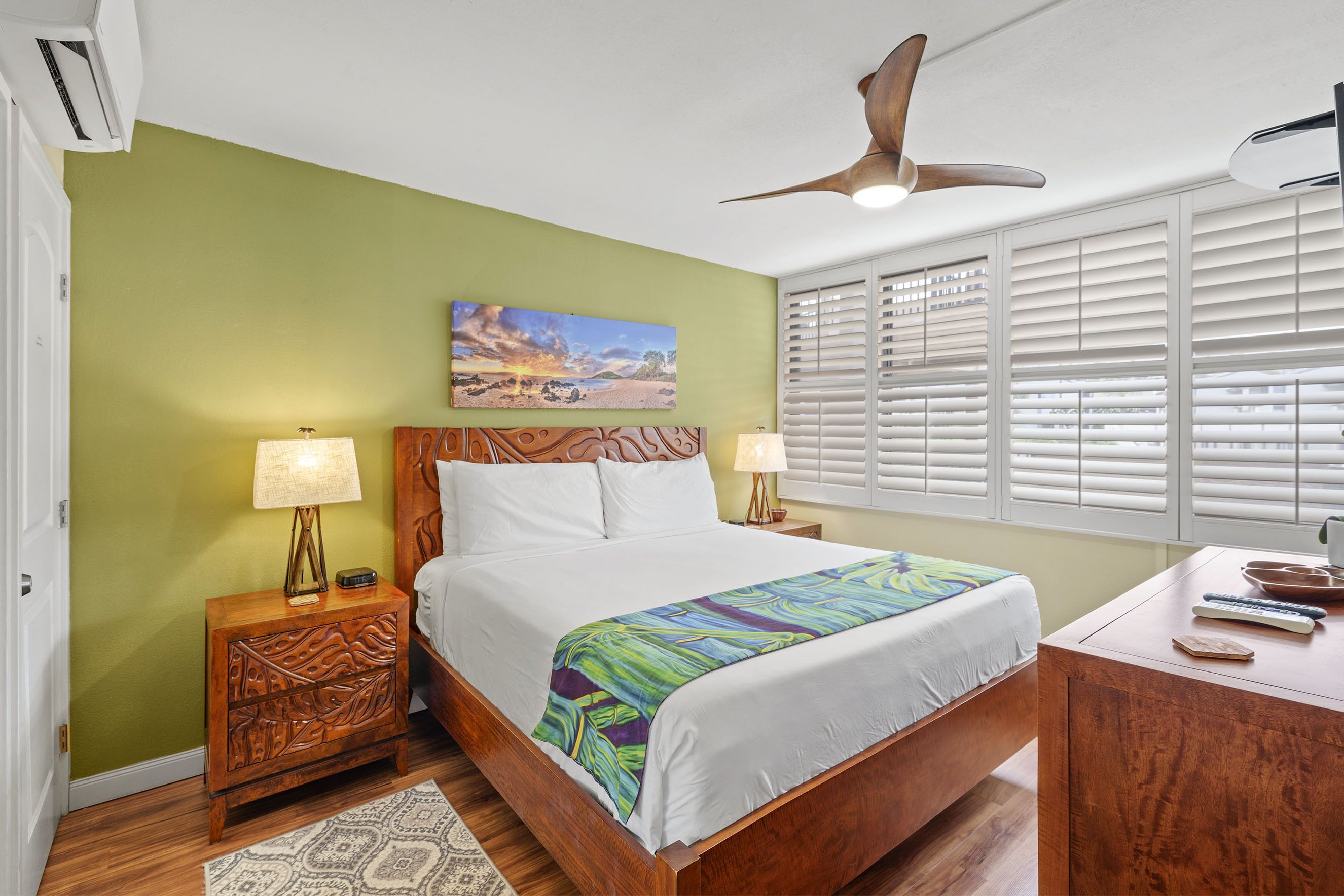 A bedroom with a bed, nightstands, a desk, and a ceiling fan.