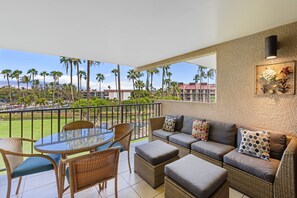 A balcony with wicker furniture, a glass table, and a sofa with patterned cushions. - Kamaole Sands 10-307, Ocean View, Large Lanai, Twin Murphy Beds, Split-ac, Wi-fi (Kihei)