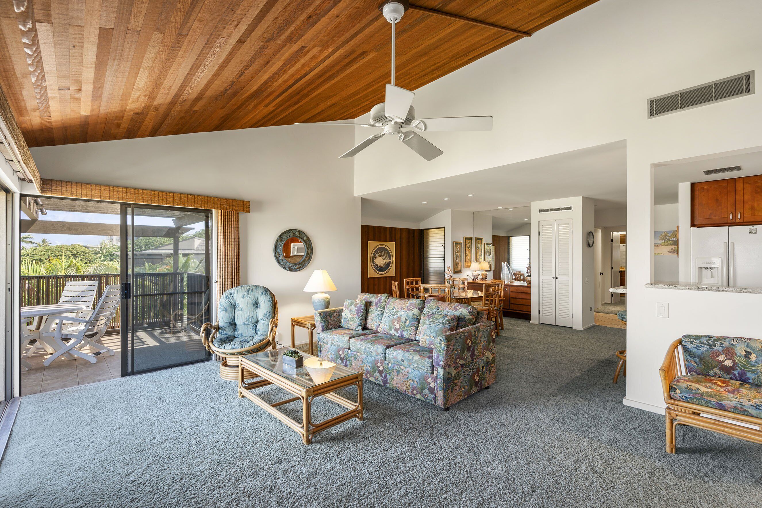 A spacious living area with a ceiling fan, a sofa, a coffee table, and a dining area with chairs and a table.