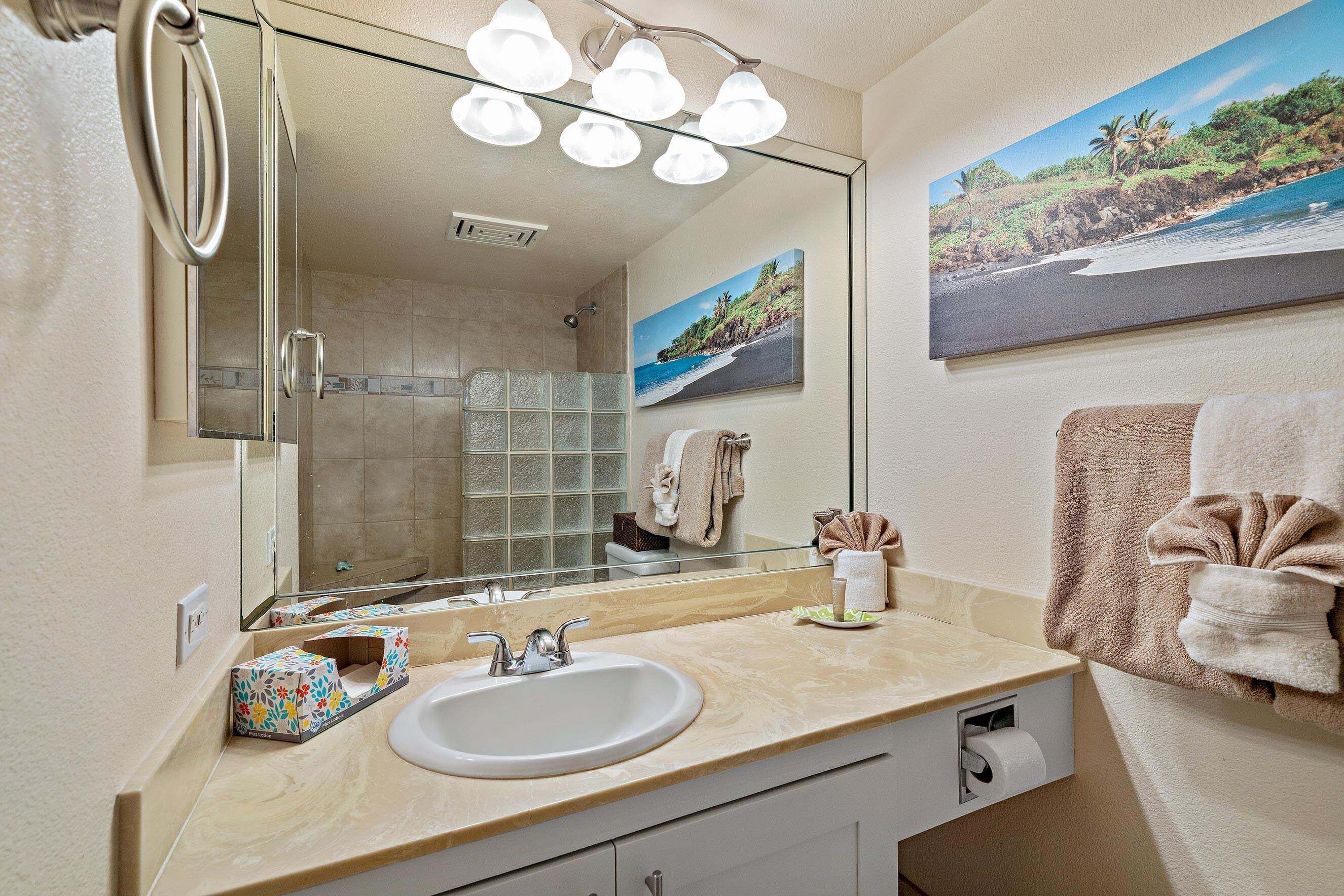 A bathroom with a large mirror, a sink, a shower, and a towel rack.