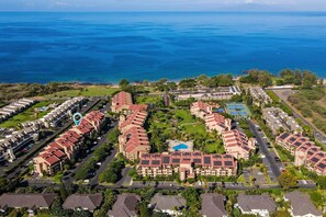 A coastal resort with multiple buildings, a parking lot, and a view of the ocean. - Kamaole Sands 9-301 - Luxurious Renovation, Split AC, Wi-fi, Ocean View Condo (Kihei)