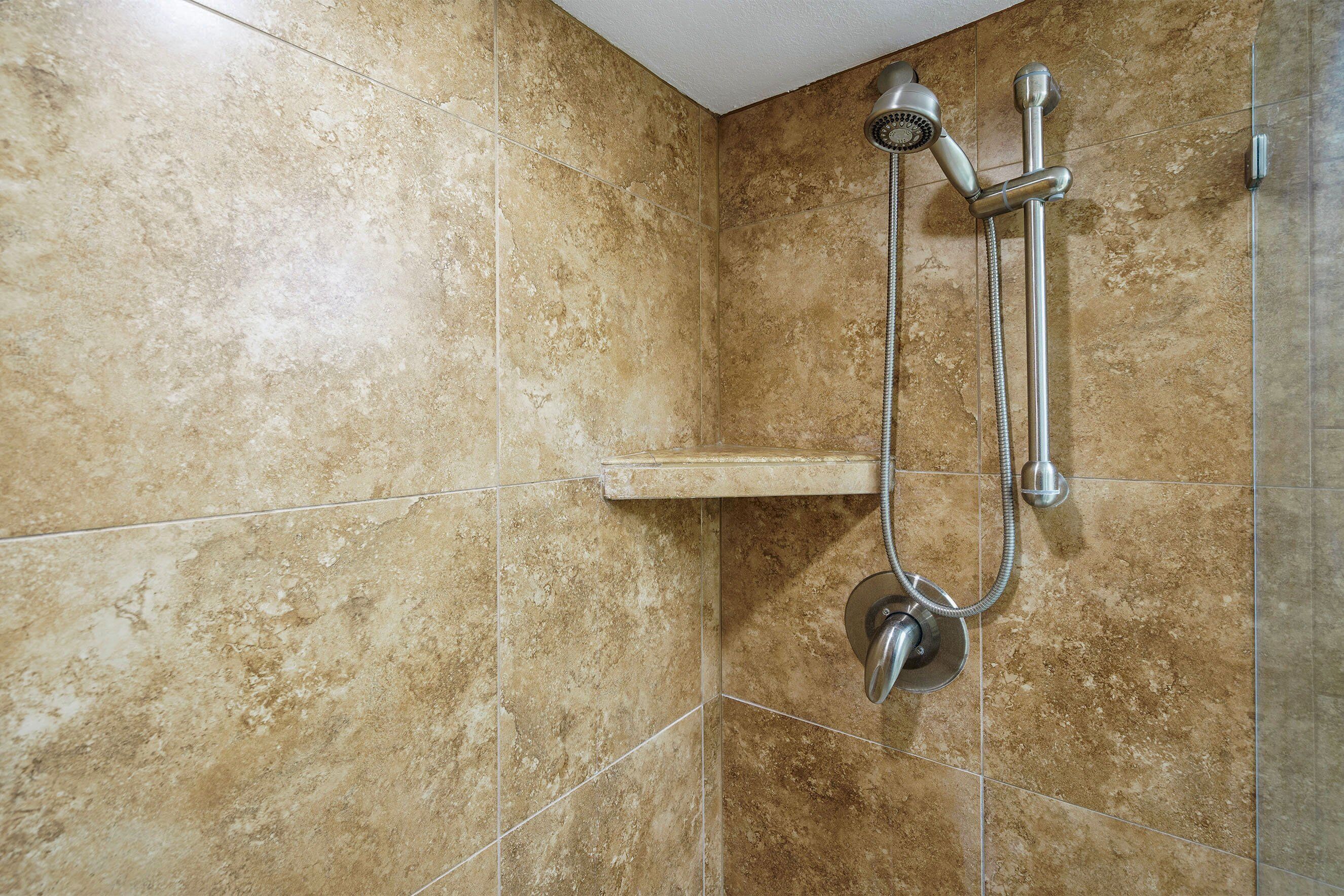 Un espace douche équipé d’un pommeau de douche à main et d’un robinet fixé au mur.