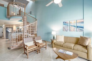A spacious living area with a wooden spiral staircase, a beige sofa, and a coffee table. - Kamaole Sands 1-403 - Ultimate Getaway! Spacious 2/2 With Split AC, Large Lanai (Kihei)