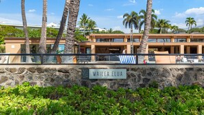 Un edificio con un muro de piedra y un letrero que dice 'WAILEA ELUA'.