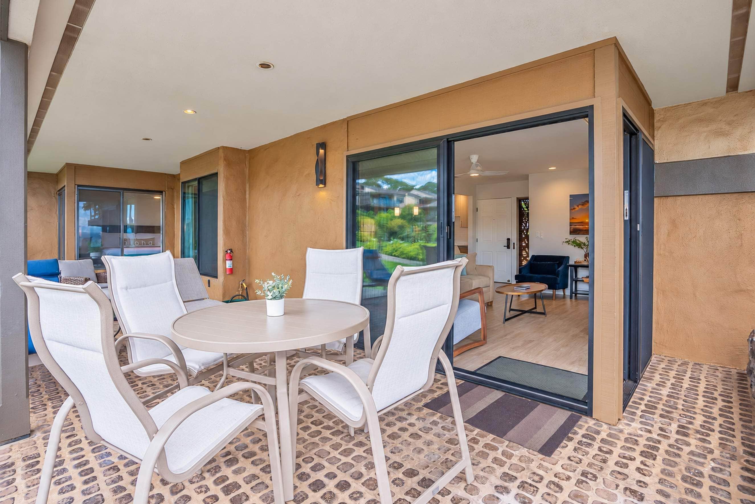 A modern interior with a round dining table, white chairs, and a view through a glass door to an outdoor area.