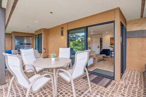 A modern interior with a round dining table, white chairs, and a view through a glass door to an outdoor area. - Luxurious Oceanfront Condo at Wailea Elua Village - Unit 1201, Central AC, Wi-fi (Kihei)