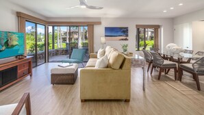 Una sala de estar amplia con un sofá grande, una mesa de comedor con sillas y un televisor.