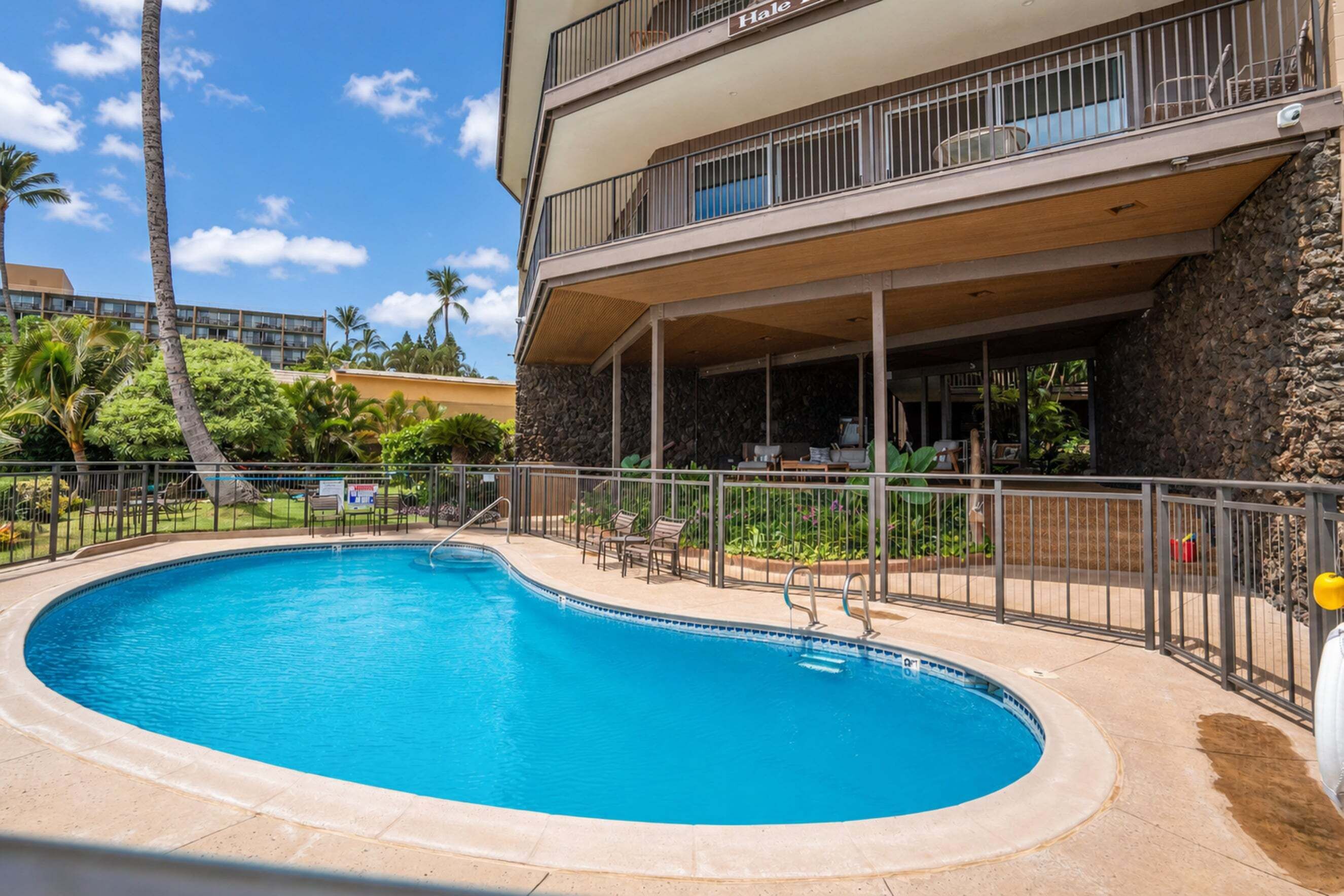 Una piscina con una parete in pietra e una zona patio coperta.