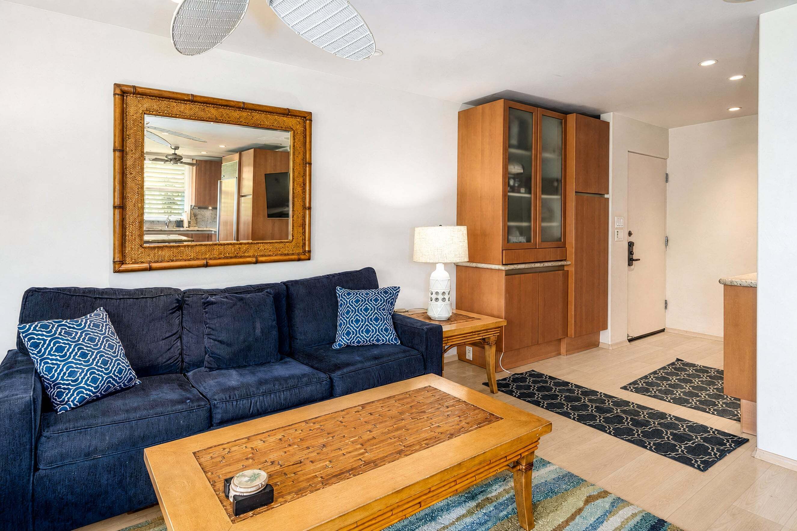 A living room with a dark blue sofa, a wooden coffee table, and a large mirror on the wall.