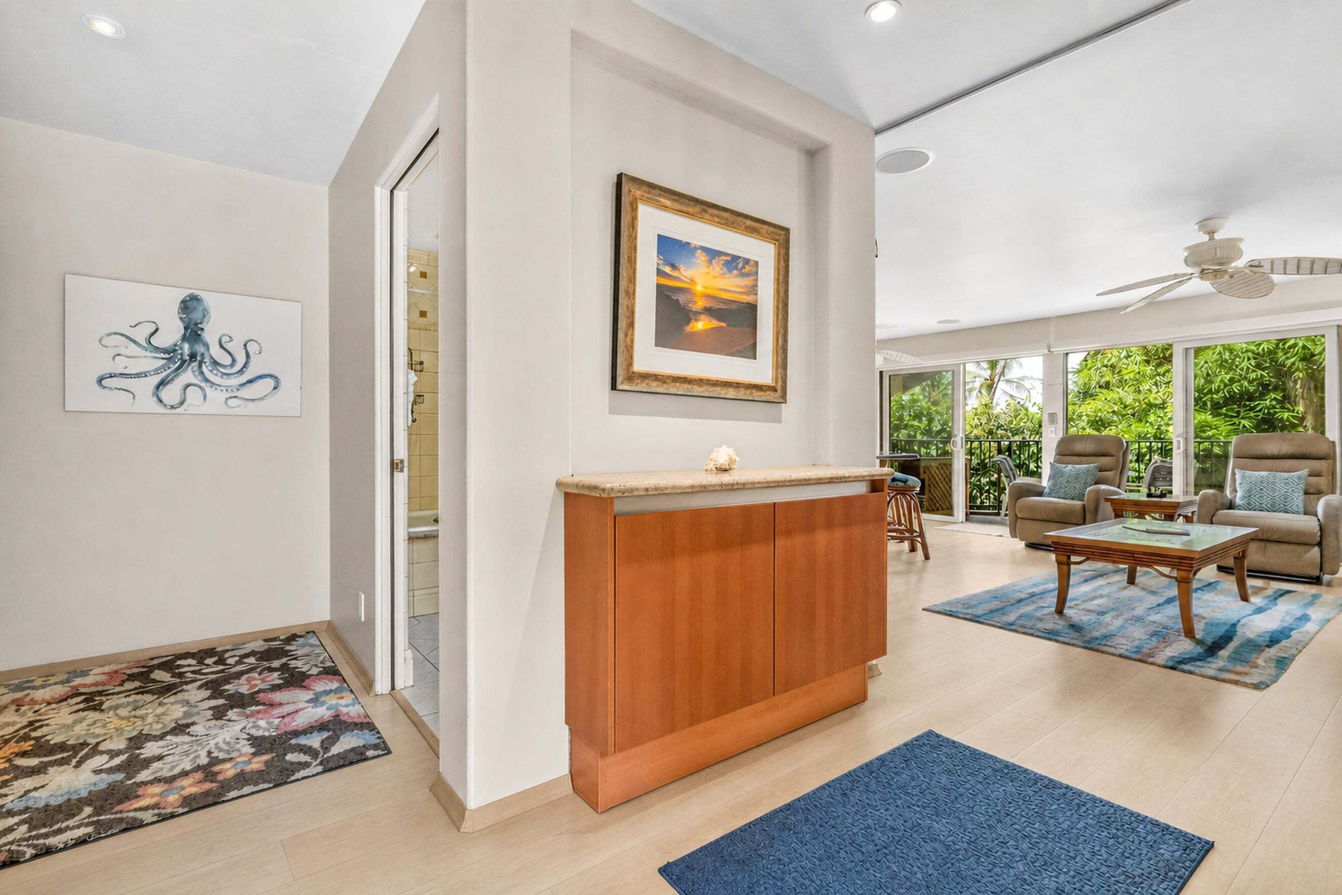 A spacious living area with a wooden cabinet, a framed picture, and a ceiling fan.