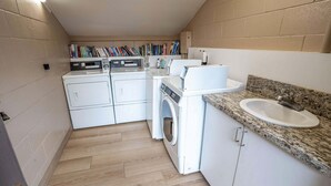 A compact laundry room with a washing machine, dryer, and a sink with granite countertop. - Hale Hui Kai 208 - Ocean View Luxury Condo on the Best Beach on Maui, Split AC! (Kihei)