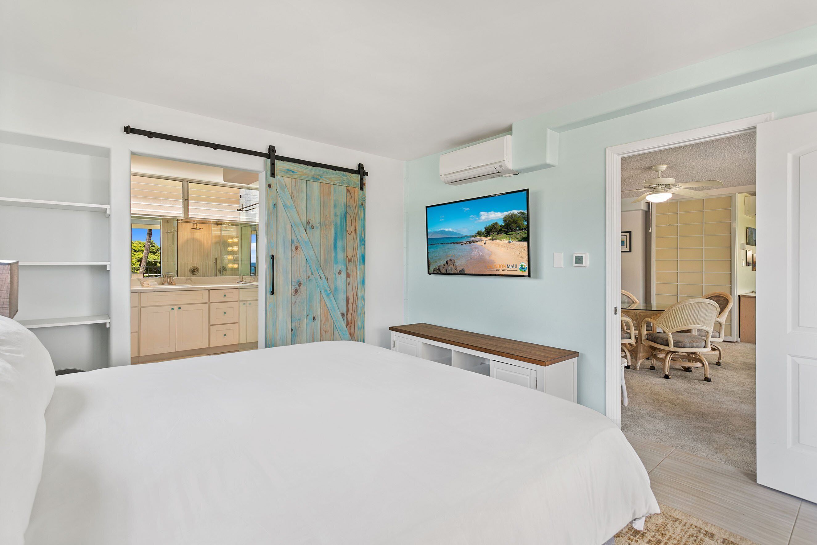 Een slaapkamer met een bed, een bureau en een stoel. Er is een schuifdeur naar een badkamer.