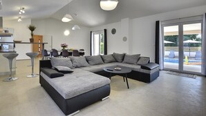 Una sala de estar moderna con un sofá seccional, una mesa de centro redonda y un comedor con una mesa y sillas.