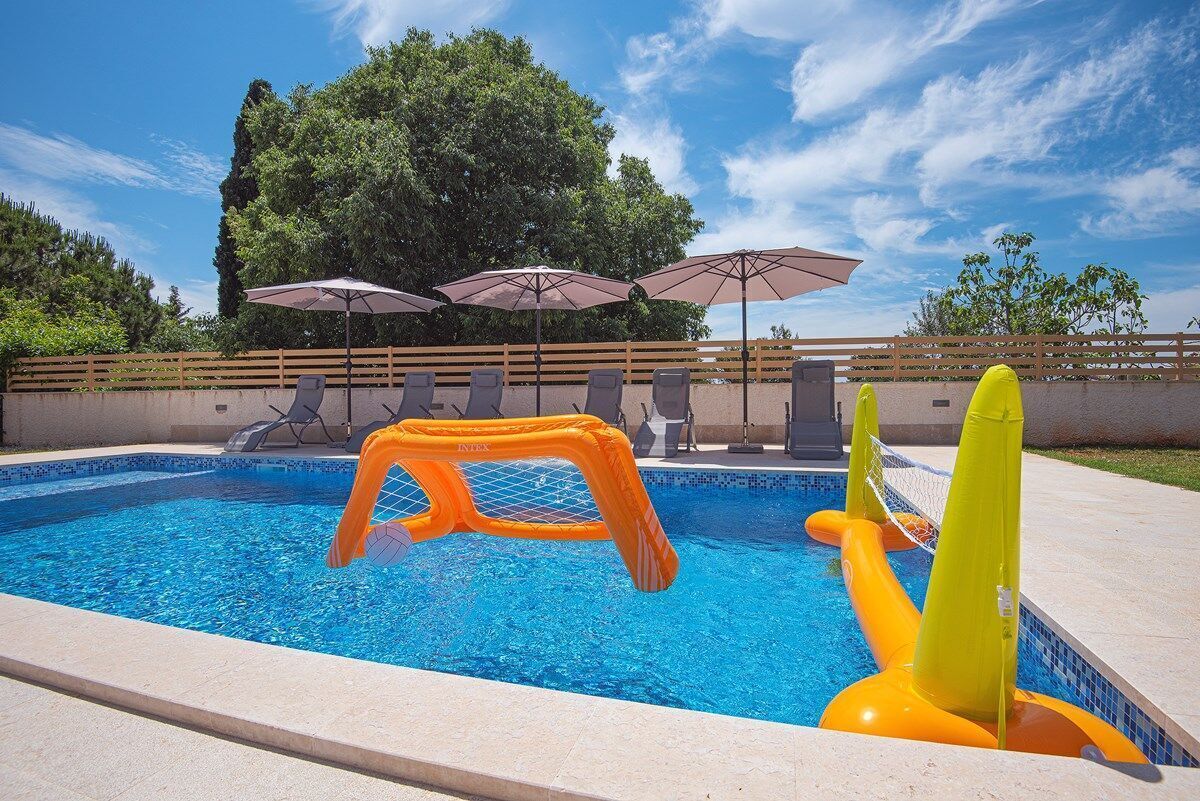 A swimming pool with inflatable play structures and lounge chairs.