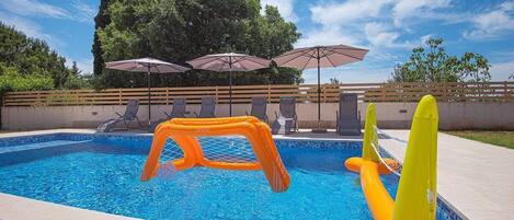 A swimming pool with inflatable play structures and lounge chairs.