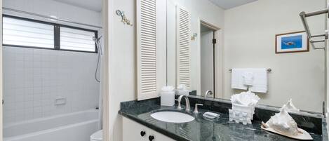 Une salle de bain avec une baignoire, des toilettes, un lavabo et un grand miroir.