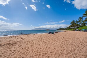 Ein Strand mit Sand, ein klarer Himmel und ein entfernter Berg.