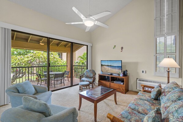 A spacious living room with a ceiling fan, a sofa, a coffee table, and a TV. - Wailea Ekahi 20J - Secluded Garden Oasis Surrounded by Trees & Tropical Blooms (Kihei)