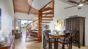 Un'ampia cucina con una scala in legno, una zona pranzo con un tavolo in vetro e un armadietto con la scritta 'CHEERS'.