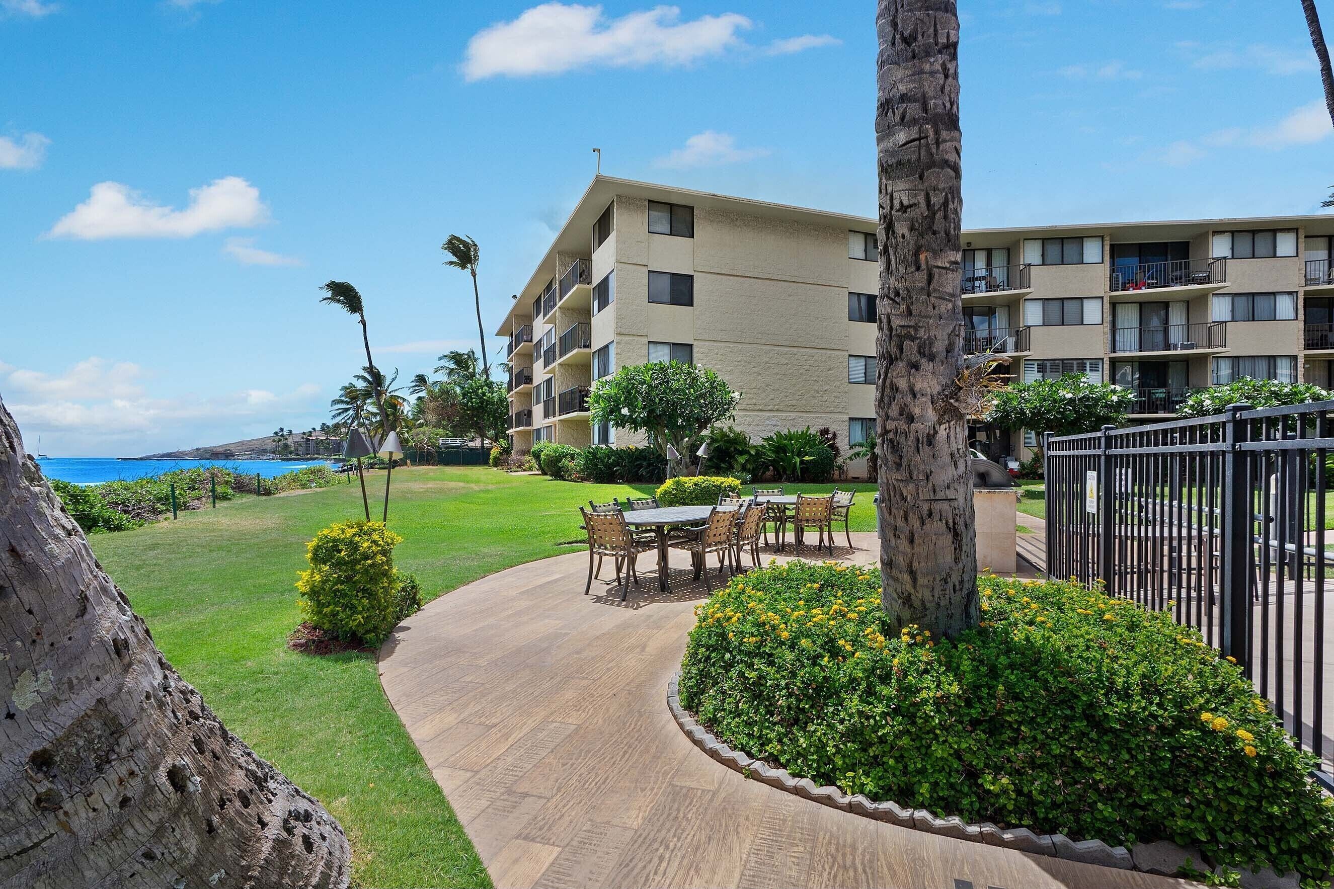 A hotel with a pool area, outdoor seating, and a view of the ocean.
