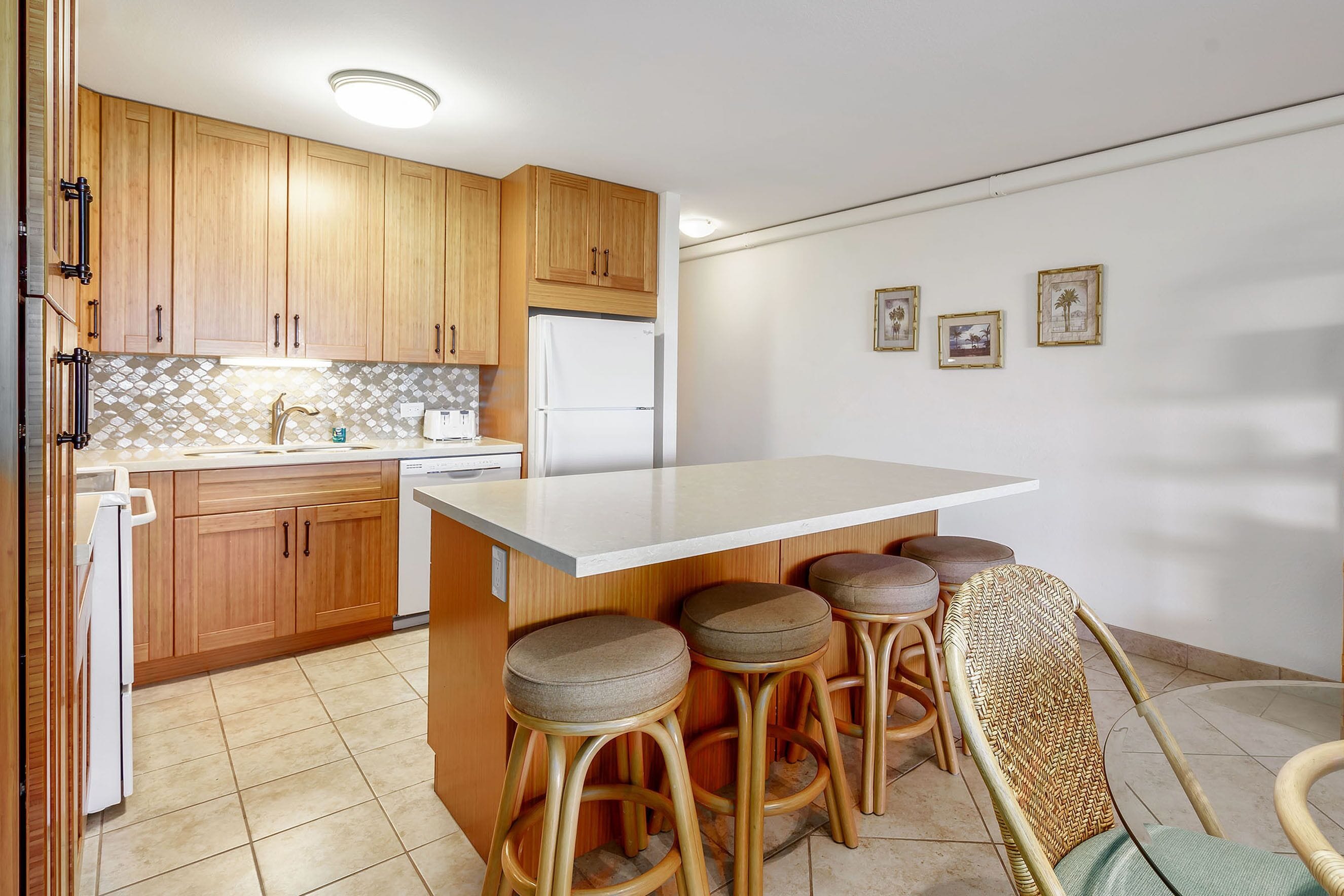 A kitchen with wooden cabinets, a white countertop, and four bar stools.