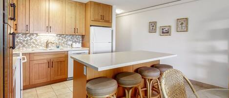 A kitchen with wooden cabinets, a white countertop, and four bar stools.