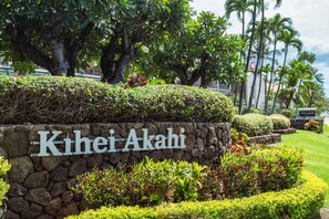 Eine Steinsäule mit der Aufschrift "Kihei Akahi" und üppigem Grün umgeben.