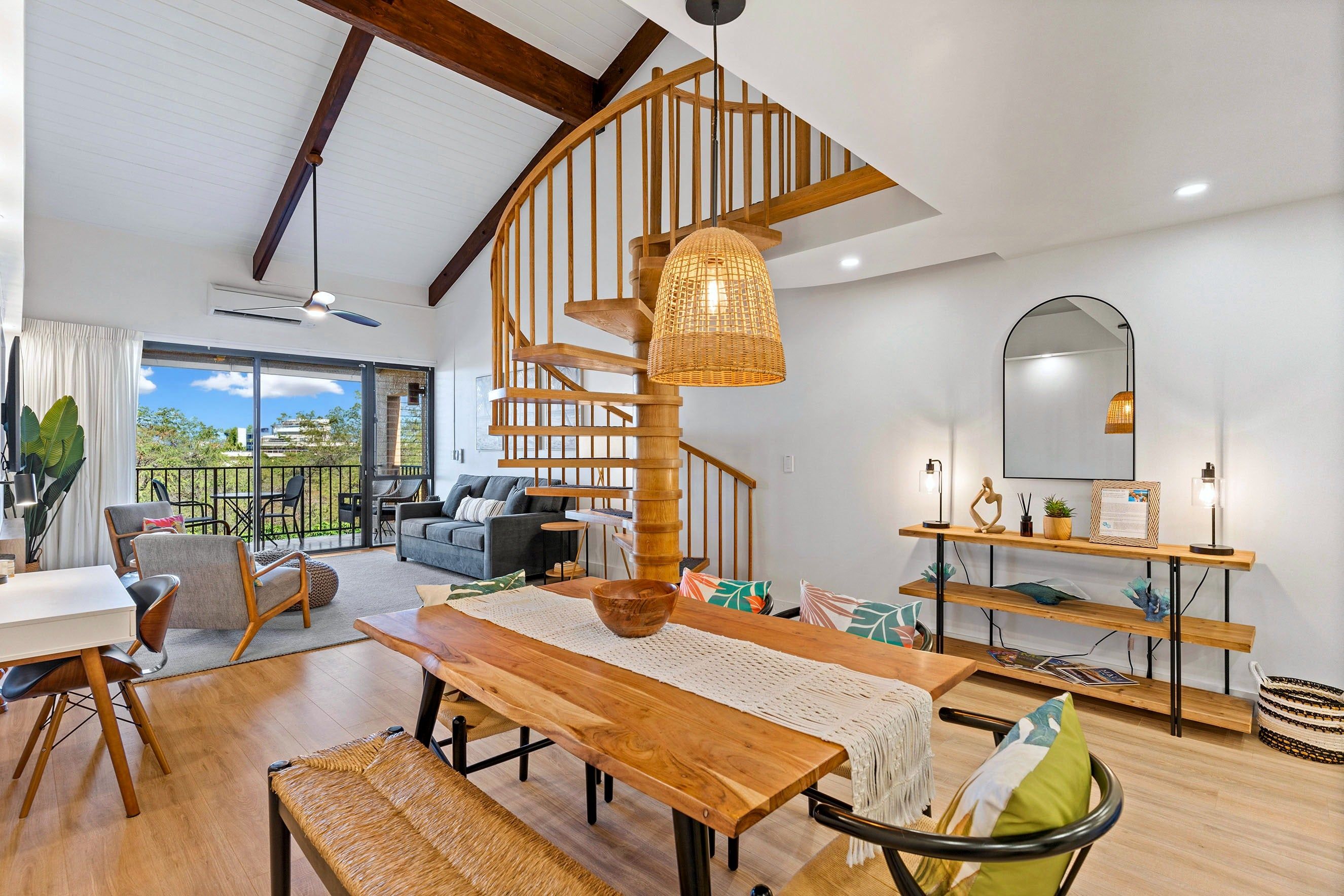 Un espacio habitable amplio con una escalera espiral de madera, una mesa de comedor y vistas al exterior.