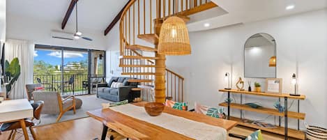 Un espacio habitable amplio con una escalera espiral de madera, una mesa de comedor y vistas al exterior.