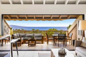Un balcon avec vue sur la mer, aménagé avec un canapé, des fauteuils et une table.