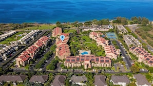 Un hotel costero con varias construcciones, una piscina y vistas al océano.