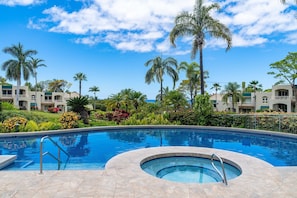 Ein Pool mit Whirlpool, umgeben von Palmen und einem angelegten Garten.