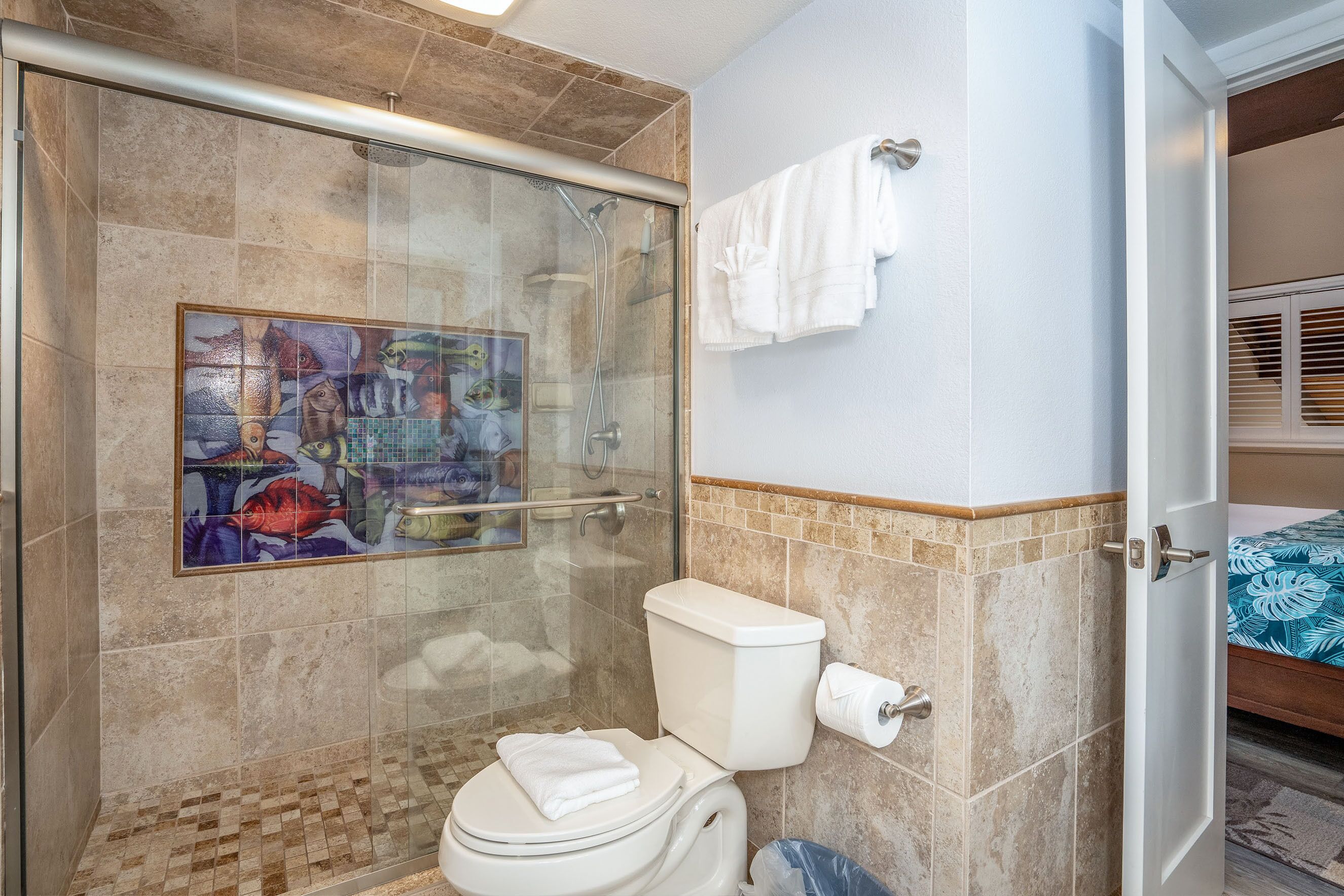 Un baño con ducha de vidrio, inodoro y perchero para toallas.
