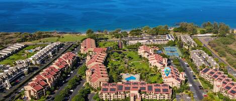 Vista aérea de un resort con varias edificaciones, una piscina y vista al océano.