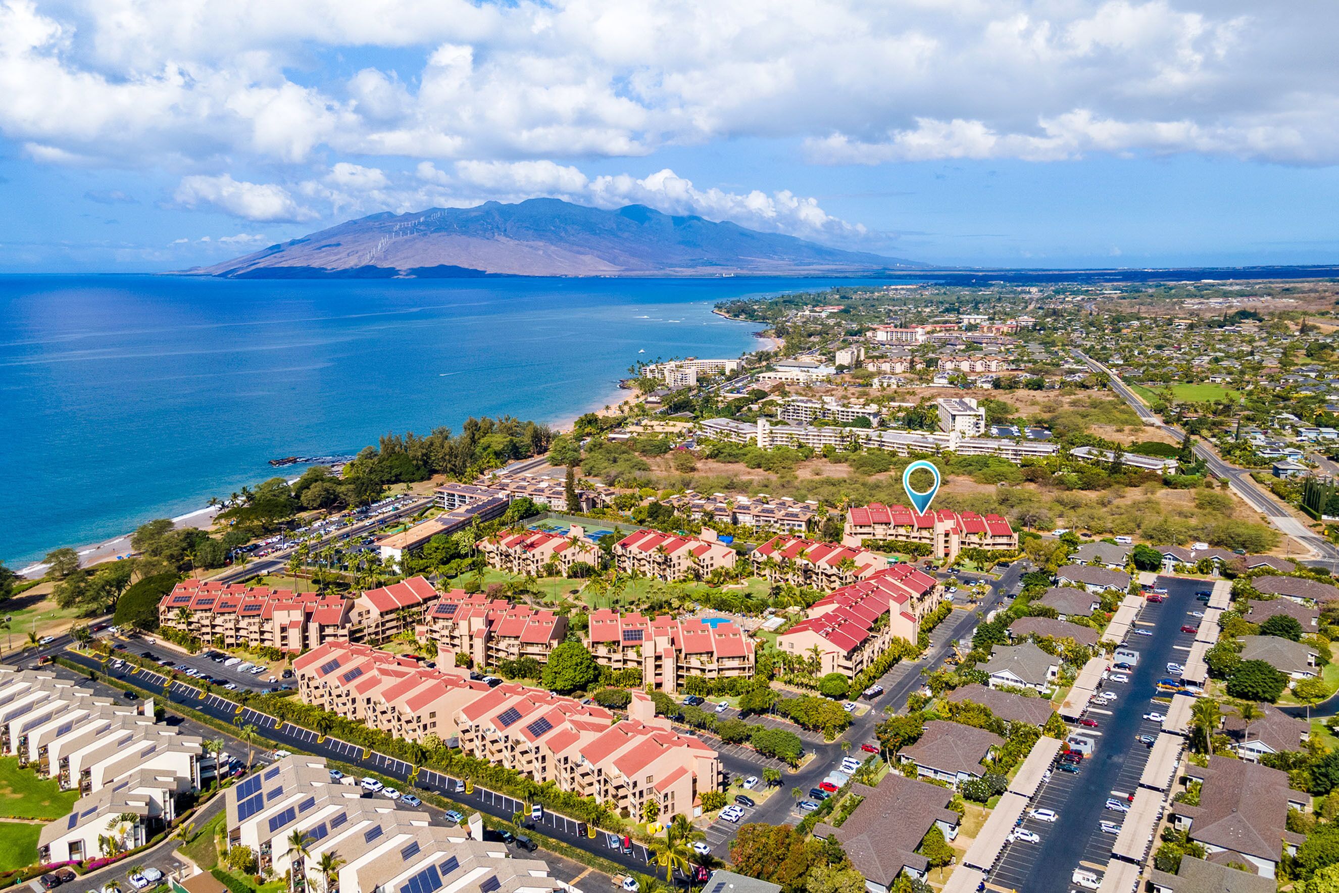 Vue aérienne d’une zone résidentielle côtière, avec des immeubles d’appartements, des routes et une vaste étendue d’eau.