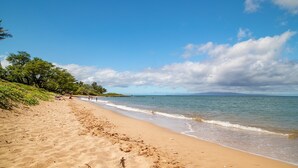 A sandy beach with gentle waves, a clear sky, and distant mountains. - Kihei Garden Estates C-201, Ocean Views, Near the Beach, Renovated, w/ Split AC! (Kihei)