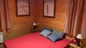 Une pièce en bois avec un lit, des oreillers, une lampe et deux tableaux encadrés accrochés au mur.