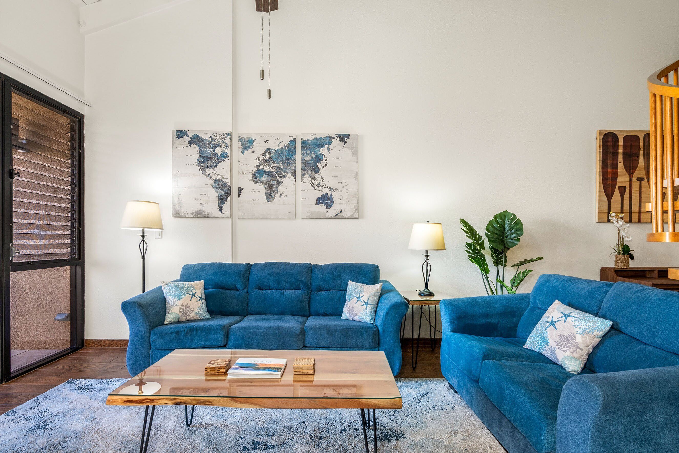 Ein Wohnzimmer mit zwei blauen Sofas, einem Holztisch und zwei Stehlampen.