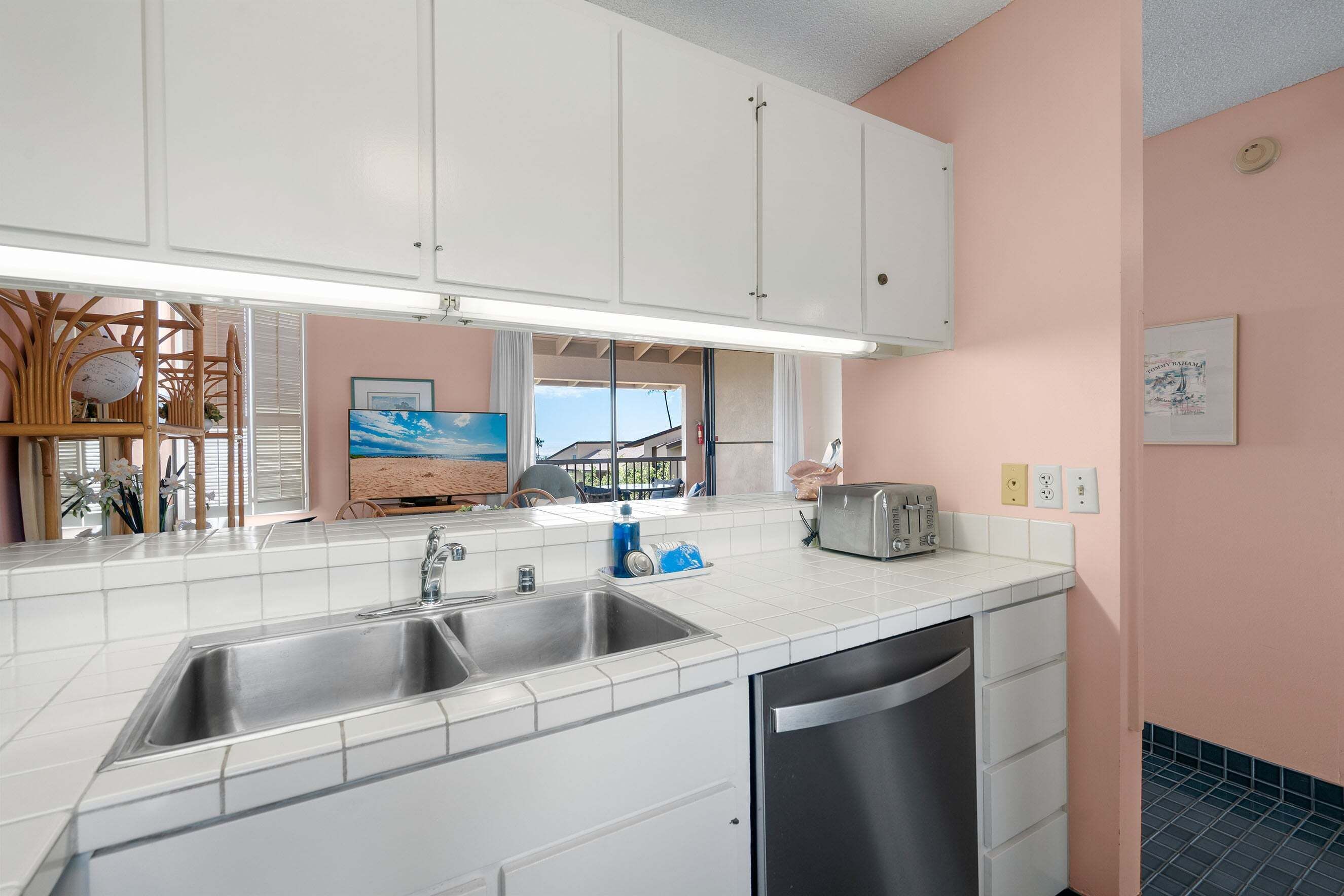 A kitchen with white cabinets, a double sink, and a dishwasher.