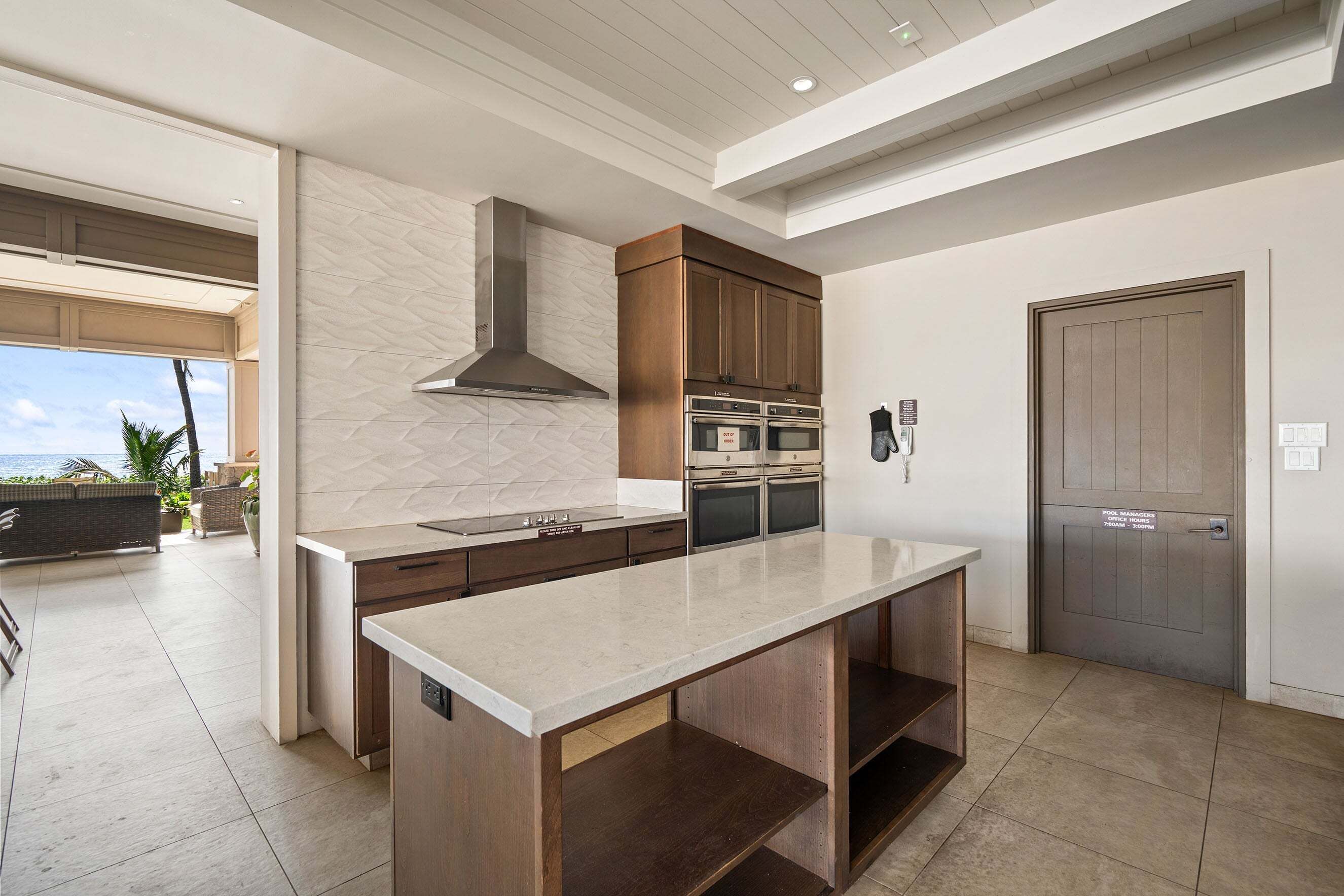 Una cocina moderna con una isla grande, hornos integrados y vistas al exterior.