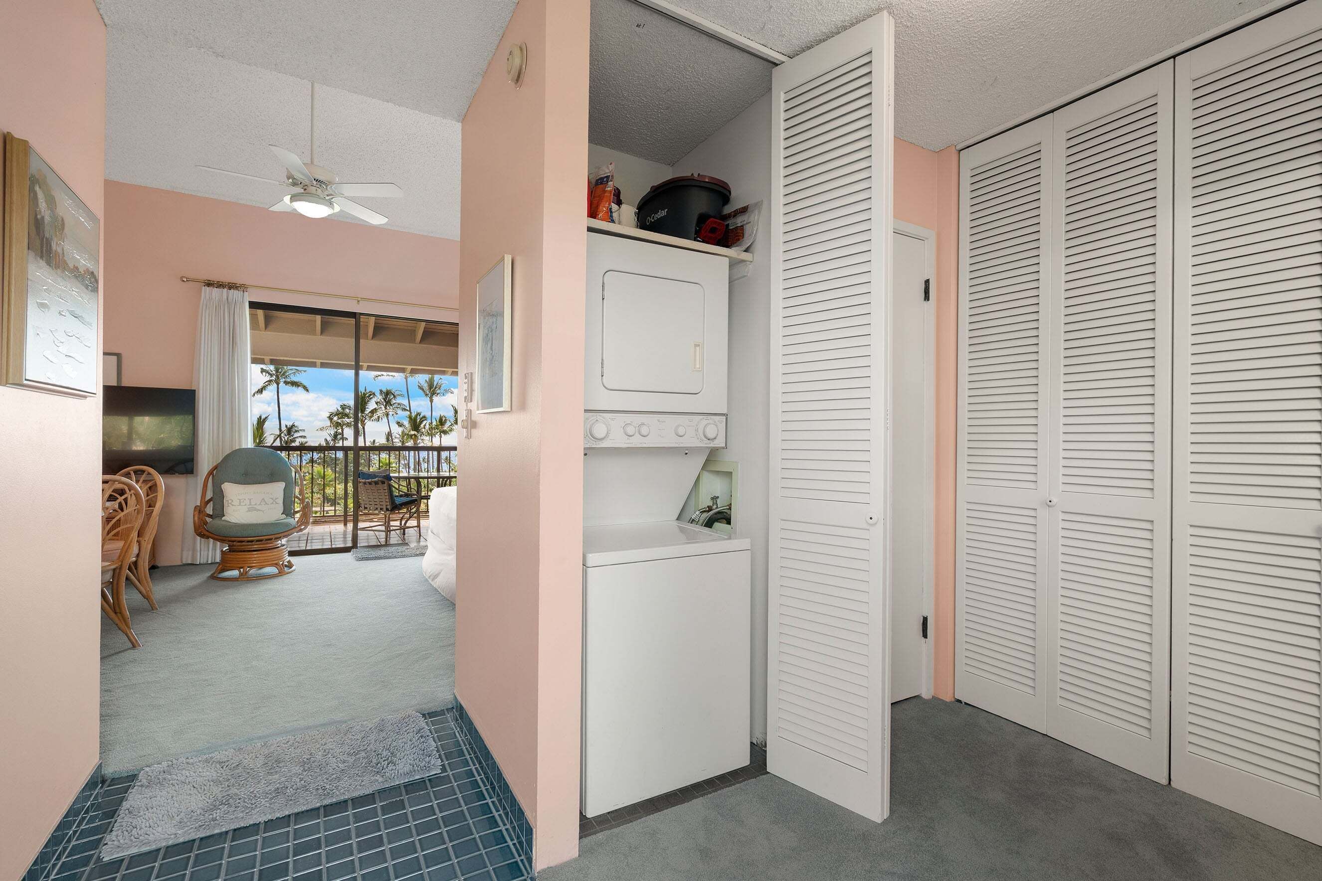 A laundry area with a washing machine, a ceiling fan, and a view of the outdoors.