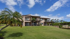 A modern two-story house with a large lawn, palm trees, and a clear blue sky. - Wailea Ekahi 12D - Budget Friendly Ocean View Studio w/ Lanai, Kitchen, WD, & AC (Kihei)