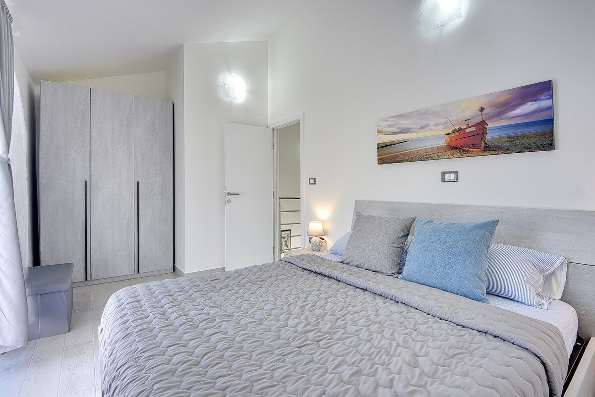 Une chambre à coucher avec un lit, une armoire et un tableau accroché au mur.