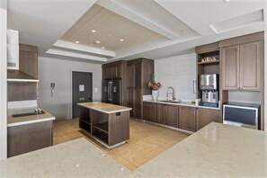 A modern kitchen with wooden cabinets, stainless steel appliances, and a marble countertop. - Wailea Ekahi 24B - Modern Garden Retreat w/ Lanai, Split AC & Stylish Renovation (Kihei)